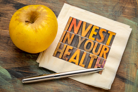 invest in your health concept - word abstract in vintage letterpress wood type on a napkin with apple, healthy lifestyle adviceの写真素材