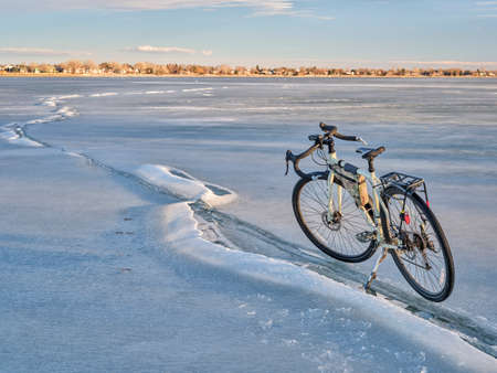 winter biking, touring or commuting - bicycle on a frozen lake, Boyd Lake State Park in northern Coloradoの写真素材