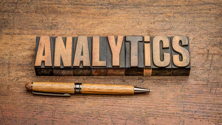 analytics word abstract in vintage letterpress wood type against weathered wooden background, business, data, statistics and research conceptの写真素材
