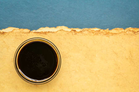 a small bowl of yacon syrup against abstract paper landscape with a copy space,  a powerful prebiotic sweetener derived from the yacon rootの写真素材