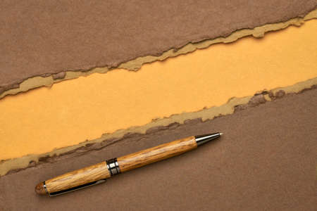 paper abstract in brown and orange with a copy space and a stylish pen - sheets of handmade paper,  diagonal blank web bannerの写真素材
