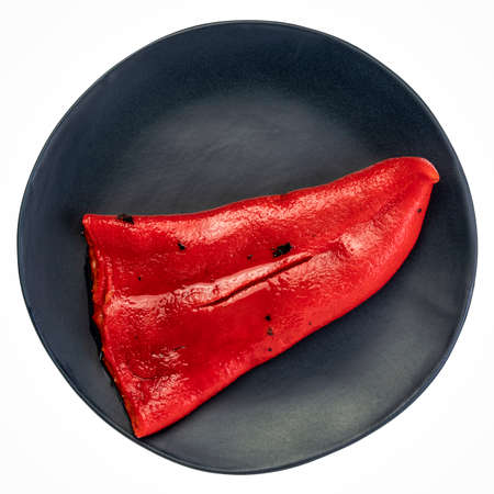 red roasted pepper on an isolated black ceramic plateの写真素材