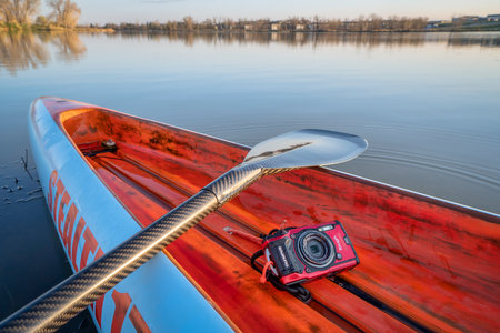 Fort Collins, CO, USA - May 6, 2021: Compact, waterproof Olympus Stylus Tough TG-5 camera on a rear deck of a stand up paddleboard by Mistral, early spring lake scenery in Colorado.のeditorial素材