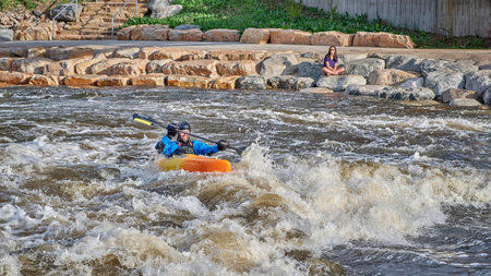 Fort Collins, CO, USA - May 7, 2021: Young male kayaker surfing a wave in the Poudre River Whitewater Park.のeditorial素材