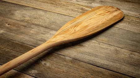 blade of wooden canoe paddle against rustic weathered woodの写真素材