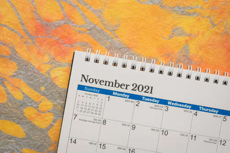 November 2021 - spiral desktop calendar against abstract marbled paper, time and business conceptの写真素材