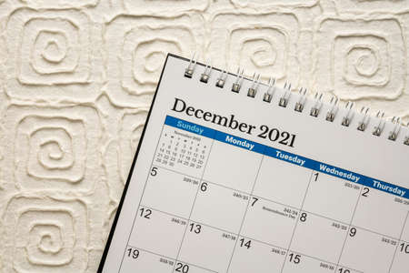 December 2021 - spiral desktop calendar against white handmade paper, time and business concept