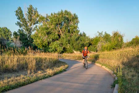 Senior male cyclist is commuting on a bike trail in Fort Collins in northern Colorado, late summer sceneryの写真素材