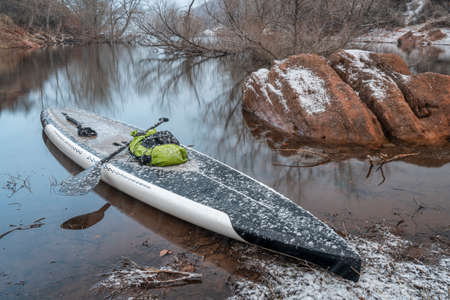stand up paddleboard in snow blizzard on a mountain lake - Horsetooth Reservoir in northern Colorado, training, fitness and recreation conceptの写真素材