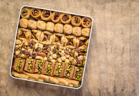 assortment of traditional Turkish baklava pastry in a tin box against handmade paper with a copy space, a dessert is well also known as Persian or Lebanese baklavaの写真素材