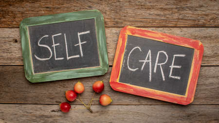 self care - white chalk handwriting on a retro slate blackboards against weathered wood - mental, emotional, and physical health conceptの写真素材