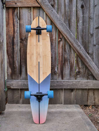 cruising longboard against a rustic wooden gate in a backyard, recreation conceptの写真素材