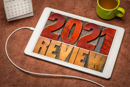 2021 year review banner - annual review or summary of the recent year - word abstract in letterpress wood type blocks on a digital tablet with a cup of coffeeの写真素材
