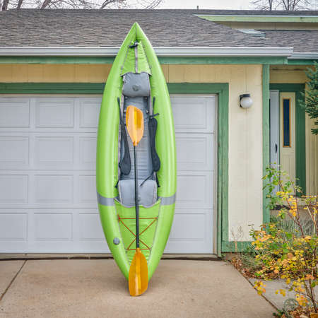 green inflatable whitewater one person kayak with a paddle in a driveway ready for a paddling tripの写真素材