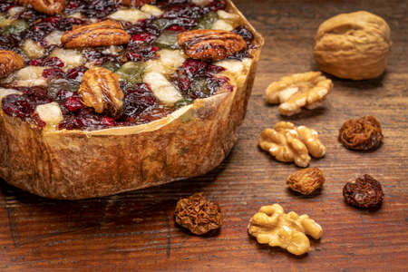 holiday rum cake with pecans, cherry,  walnuts and goldenberry on a grunge, weathered wood