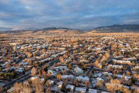 November sunrise over city of Fort Collins (residential area) and Front Range of Rocky Mountains in northern Colorado, aerial view in fall scenery with some snowの写真素材