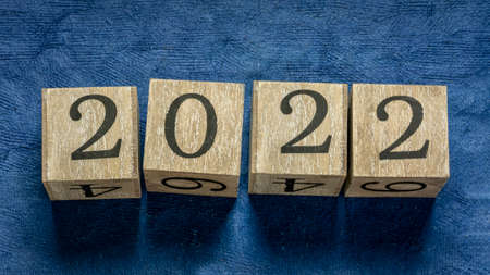 2022 year in rustic wooden blocks against blue, textured, handmade paper, New Year concept