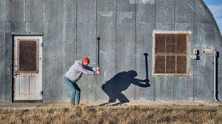 senior athletic male is exercising with a steel mace with a company of a shadow on a grunge metal...