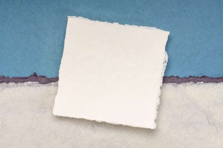 small square sheet of blank white Khadi paper against blue rag paper abstract