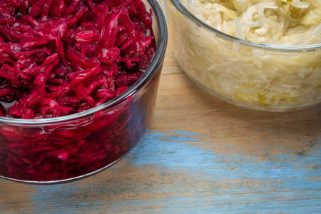 bowls of organic, red beets and cabbage sauerkraut against grunge wood, prebiotics concept - fermented food good for gut healthの写真素材