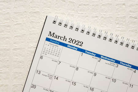 March 2022 - spiral desktop calendar  against white embossed paper, time and business conceptの写真素材