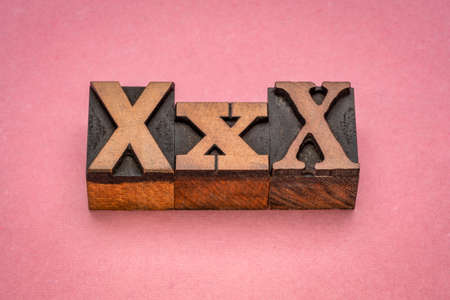xxx symbol in vintage letterpress wood type against pink textured paper - adult content, entertainment and pornography conceptの写真素材