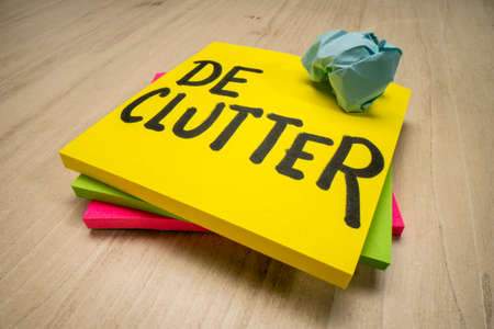 declutter reminder - handwriting on a sticky note against wooden table, productivity, business or lifestyle conceptの写真素材
