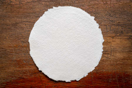 circular sheet of blank white watercolor paper against rustic weathered woodの写真素材