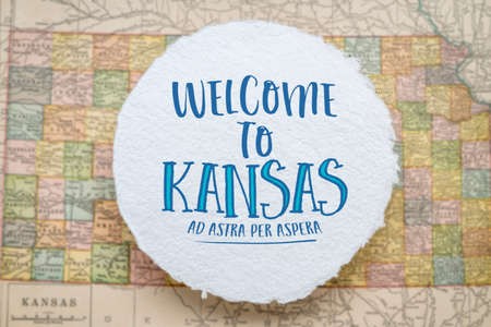 welcome to Kansas, ad astra per aspera - handwriting on a circular sheet of rough handmade paper floating over vintage defocused map of Kansas, hospitality and travel conceptの写真素材