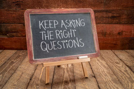 keep asking the right questions inspirational reminder - white chalk handwriting on a slate blackboard, easel sign against rustic, weathered wood, education, business and science conceptの写真素材