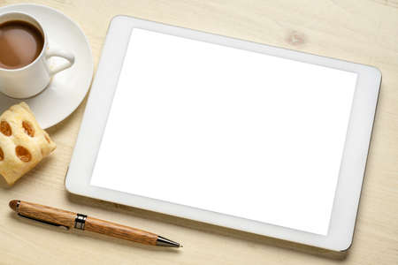 mockup of digital tablet with a blank isolated screen, flat lay with a cup of coffee and cookie on...