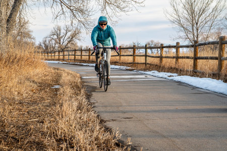 Windsor, CO, USA - February 9, 2022 - Male cyclist is biking on the Poudre River Corridor trail in...