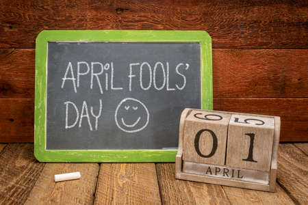 April Fools' Day - white chalk handwriting on a vintage slate blackboard with wooden calendarの写真素材