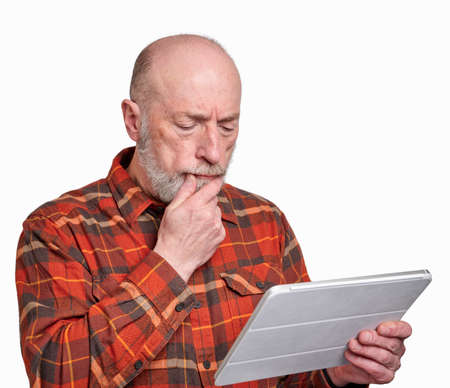 senior man is reading or watching news on a digital tablet and looks worrying and concerned