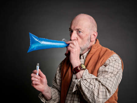 Head and shoulders portrait of a senior man performing breath test to diagnose SIBO (small...