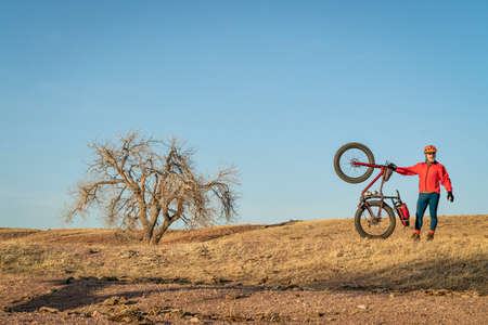 senior male cyclist with a fat mountain bike in northern Colorado prairie, early spring scenery in Soapstone Prairie Natural Area near Fort Collinsの写真素材