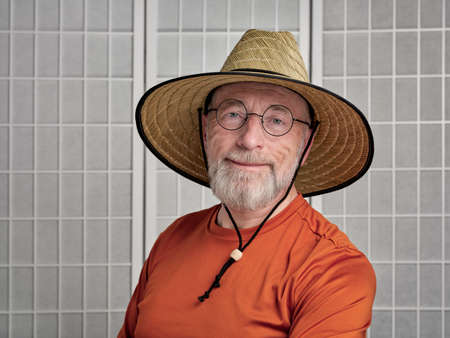 casual portrait of happy and smiling senior man wearing straw sun hat