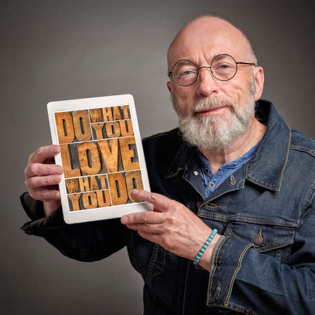 do what you love, love what you do - senior man sharing inspirational message on a digital tablet, personal development and healthy lifestyle conceptの写真素材