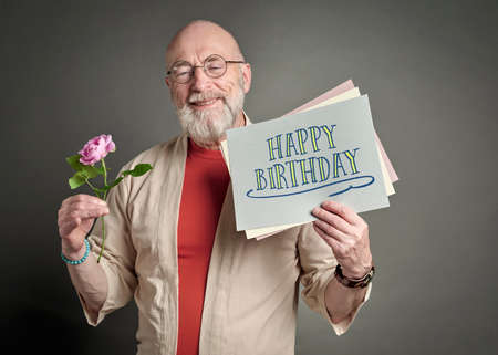 Happy Birthday - smiling senior man with pink rose and greeting card