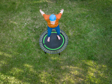 aerial view of a senior man is exercising on a mini trampoline in his backyard backyard, fitness and...