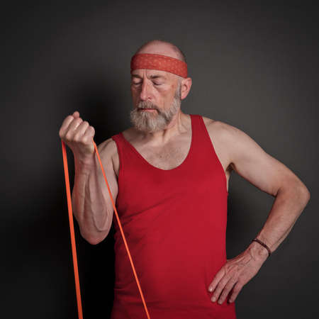 head and shoulder portrait of senior man (in late 60s) exercising with resistance band,  fitness...