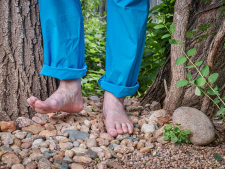 garden path for feet massage, senior man is walking barefoot on pebbles and gravel in his backyard