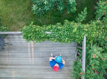 senior man is exercising with a heavy slam ball on his backyard patio, top aerial viewの写真素材