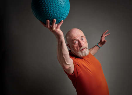 senior man (in late 60s) is exercising with a heavy slam or medicine  ball, activity and fitness over 60 conceptの写真素材