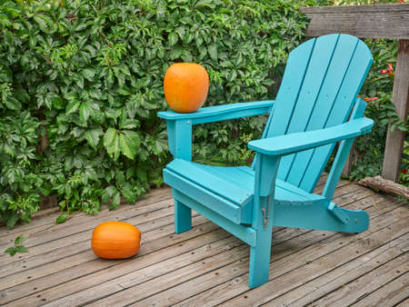 empty Adirondack chair with pumpkins on a wooden backyard deck, late summer or fall scenery in Coloradoの写真素材