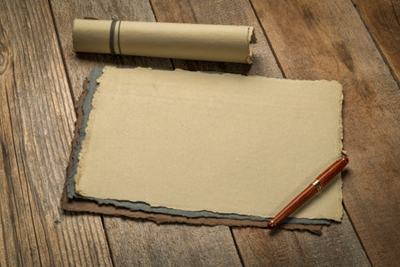sheets of blank handmade paper with rough edges and a stylish pen against rustic weathered woodの写真素材