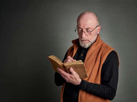 Head and shoulders portrait of bald and bearded senior man writing a journalの写真素材