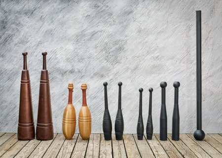 row of traditional exercise equipment - Persian meels, Indian clubs, steel clubs and steel mace on a rustic wood deck against grunge wall with a copy spaceの写真素材