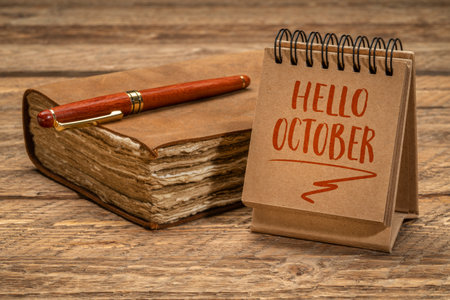 Hello October welcome note  - handwriting in a spiral desktop calendar of notebook with a retro journal, season and calendar conceptの写真素材