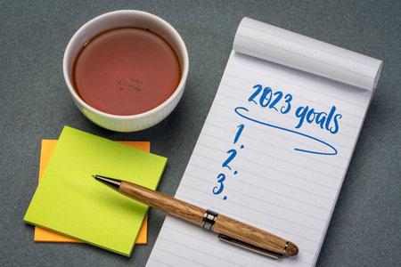 2023 goals list in a notebook with pen and reading glasses, setting New Year goals and resolutionsの写真素材